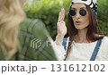 Stylish women chatting outdoors in casual fashion with sunglasses and headscarves 131612102