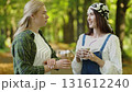 Two friends share a moment in a sunlit park while enjoying coffee and laughter 131612240