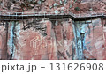 Aerial view of a wooden walkway built along a dramatic cliff face surrounded by lush green forest, showcasing adventure travel, hiking trails, and natural scenic beauty, Phu thok temple, Thailand 131626908