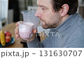 Handsome man making pink smoothie from fresh fruits in kitchen. Healthy food, health care nutrition. Bearded brutal athlete man drinking protein shake before training workout. Fitness dietary activity 131630707