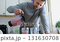 Handsome man making pink smoothie from fresh fruits in kitchen. Healthy food, health care nutrition. Bearded brutal athlete man drinking protein shake before training workout. Fitness dietary activity 131630708