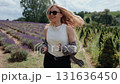 Blonde woman in sunglasses running through vibrant lavender field, hair flowing freely, embodying summer leisure and carefree joy in scenic countryside landscape. Woman sprinting across lavender field 131636450