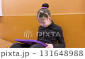 Nestled in a quiet hallway, this dedicated young figure skater finds a moment of tranquility, engrossed in her tablet as she mentally prepares for her upcoming performance. 131648988