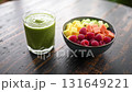 Refreshing green smoothie and colorful fresh fruit bowl on a rustic wooden table 131649221