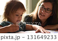 Caring mother teaching her young child to draw and color in a book at home 131649233