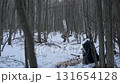 Man carrying heavy log through snowy winter forest 131654128