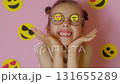 A girl with smiley stickers on her glasses blows a kiss. World Emoji Day 131655289