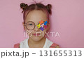 The girl decorated her glasses with multicolor puzzles as a sign of support for children with autism spectrum disorder. 131655313