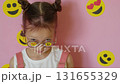 A curious inquisitive child looks through glasses with emoji stickers. Children's involvement in social media 131655329