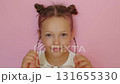 The child does not hesitate to wear Eyeglasses. A girl with a funny hairstyle and pink hair wears glasses. 131655330