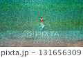 Aerial view of a man in red shorts swims in the crystal clear sea water 131656309