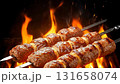 Succulent meat skewers sizzle over a roaring fire, filling the air with smoky aromas. Friends gather around, enjoying delicious food and vibrant summer vibes. 131658074