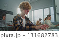 Curly Haired, Handsome Young Man in Sunny Computer Lab is Concentrating on Work at Computer 131682783