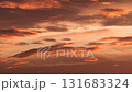 A vibrant sunset with orange and pink hues illuminating the sky. Wispy clouds create a dramatic effect against the colorful backdrop. 131683324