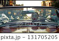 A girl driving a convertible is driving along the street of a big city during sunset. 131705205