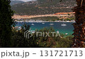Aerial view of Kas Marina in Turkey with yachts and boats anchored in turquoise water, surrounded by green hills and mountains under a clear summer sky. 131721713