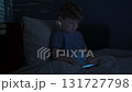 Child siting in Bed staring intently at his smartphone 131727798