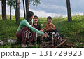 Family roasting marshmallows over campfire in forest 131729923