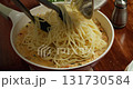 A chef tosses a tomato-spinach-cream sauce with seared salmon and flips it with a wooden spatula in a frying pan. A 4K close-up of home-cooked vegetables and fish in a rich, creamy sauce. 131730584