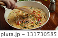 Chef sauteed tomatoes with spinach and creamy sauce, adds seared salmon, and stairs with a wooden spatula. 4K close-up of home cooking vegetables and fish in rich cream sauce. 131730585