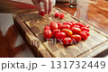 A chef cuts cherry tomatoes. Woman cutting cherry tomatoes for spaghetti with Salmon and Spinach in Creamy Sauce on wooden board with kitchen knife. 131732449