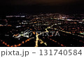 An aerial view shows a vibrant city at night, filled with shimmering lights and busy streets all around 131740584