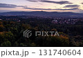 An aerial view captures a stunning landscape of rolling hills and sparkling city lights during sunset 131740604