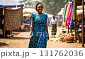 Happy young african woman in traditional dress walking at outdoor street market and smiling 131762036