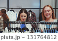 Two young women shopping in fashion store, browsing clothes on hangers, choosing stylish outfits, enjoying retail fashion and lifestyle 131764812