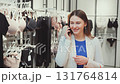 Stylish woman in fashion store talking on smartphone while shopping in lingerie section, multitasking modern lifestyle moment 131764814