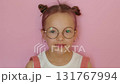 A beautiful girl with a funny hairstyle and pink hair wearing round-rimmed glasses.  Vision correction in children 131767994