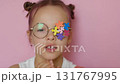 A child wearing eyeglasses with colored puzzle pieces decorated with a lens blows a kiss. Support for children with autism 131767995