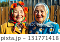 Medium close-up of two joyful senior women friends in colorful folk headscarves smiling warmly outdoors 131771418
