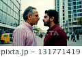 Medium shot of an older man with grey hair and a younger bearded man in a tense face-to-face confrontation on a modern city street with tall buildings and a yellow auto-rickshaw 131771419