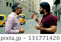 Medium shot of an older man with grey hair and a younger man with a beard engaged in an intense, animated discussion on a city street in the background under natural daylight 131771420