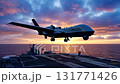 Twin-engine surveillance drone with landing gear deployed, hovering above aircraft carrier flight deck during a dramatic pink and purple sunset over the ocean, medium shot 131771426