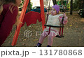 Happy toddler enjoys swinging in a park during autumn with colorful leaves on the ground 131780868