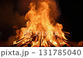 Large bonfire with bright flames creating warm gathering atmosphere as sparks fly into night sky 131785040