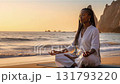 Peaceful african american woman meditating in lotus pose on the beach at a golden sunset 131793220