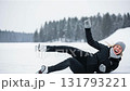 Happy young woman laughing after falling while ice skating on frozen lake in winter landscape 131793221