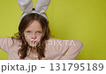 A humorous girl in a rabbit costume with a painted face makes a menacing displeased look. The feast of Holy Easter. 131795189