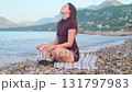 Relaxing on the coast woman meditating by the sea serenity and wellness peaceful outdoor lifestyle scene 131797983