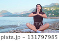 Young woman practicing yoga on seashore outdoor fitness and active lifestyle enjoying fresh air 131797985