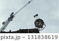 Tower crane lifting concrete bucket at construction site of tall building 131838619