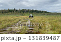 Swamp tractor powers through the marsh, selective focus. Rugged machinery meets raw nature on a handmade log road 131839487