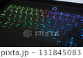 Illuminated multi-colored keyboard of a laptop displaying blue, green, and purple shades. 131845083