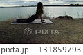 Participating in an Outdoor Yoga Practice by the Water during the Beautiful Dusk Hours 131859793
