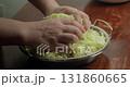 Peel the zucchini. 4K close-up: A chef transfers the sliced zucchini, chef squeezes the juice through a metal sieve onto a on a rustic table in the kitchen. 131860665