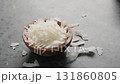 Handheld slow motion of coconut chips in olive bowl on terrazzo surface 131860805