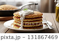 A hot stack of homemade potato pancakes or draniki with sour cream and dill on a wooden table 131867469
